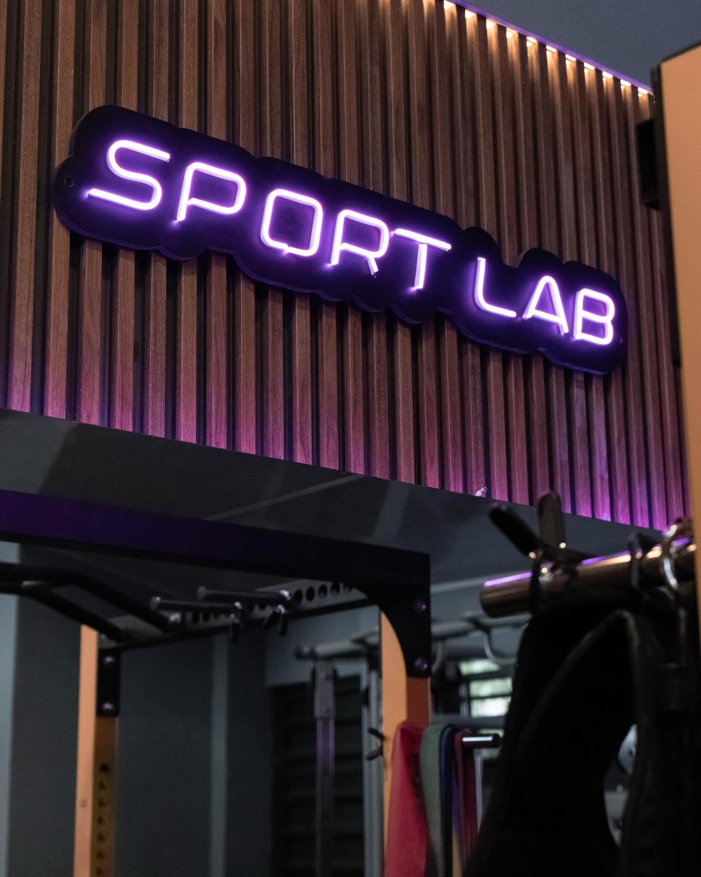 Rótulo de neón de Sport Lab sobre la pared de madera del gimnasio